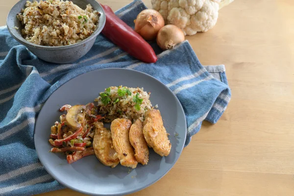 Sült csirkemell filé karfiolos rizzsel és zöldséges raguval harangpaprikából és gombából, egészséges diétás étel kék tányér és konyharuha egy fából készült asztalon, másolás — Stock Fotó