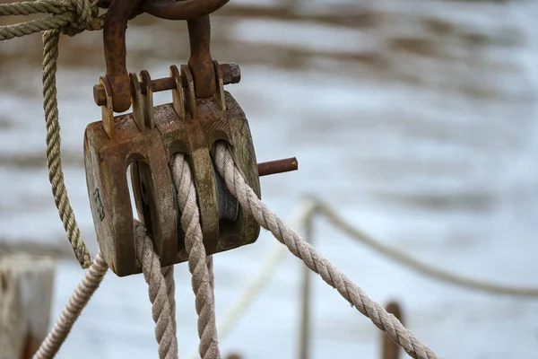 Trä pulley block med väderbeklädda rep på en historisk segelbåt mot suddigt havsvatten — Stockfoto