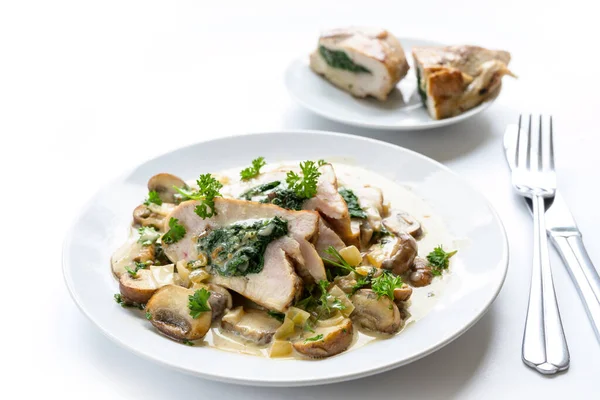 Fillet payudara ayam diisi dengan bayam, disajikan dengan jamur, hiasan peterseli dan saus gorgonzola krim di piring, latar belakang putih — Stok Foto