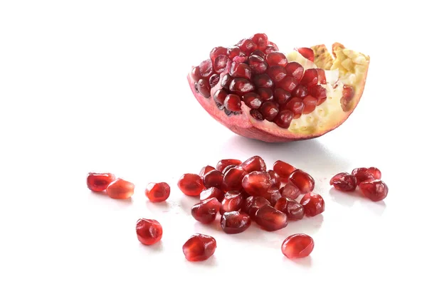 Pedazo de fruta de granada con semillas jugosas rojas aisladas con sombras sobre un fondo blanco, espacio para copiar — Foto de Stock