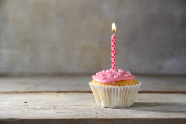 Μάφιν ή cupcake με ένα ροζ κερί σε μια ξύλινη σανίδα σε ρουστίκ φόντο, γενέθλια έννοια με αντίγραφο χώρο — Φωτογραφία Αρχείου