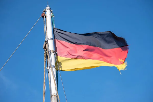 Drapeau de l'Allemagne flotte sur le mât d'un voilier contre un ciel bleu clair, espace de copie — Photo