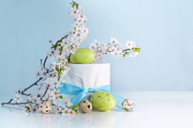Easter eggs and a decorated toilet roll with ribbon and cherry flower twigs, special holiday gift after lack of tissue during coronavirus outbreak and panic buying, light blue background with copy space, selected focus, narrow depth of field clipart