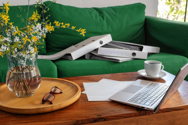 Home office in the living room, laptop on the coffee table and ring binders on the couch, exceptional working situation during the pandemic coronavirus crisis, selected focus, narrow depth of field