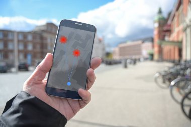 Cep telefonu ve bluetooth üzerinden salgının yayılması karşısında koronavirüs izleme uygulaması ile el ele, ancak kişisel verilerin korunması söz konusu olduğunda tartışmalı, kopya alanı olan bulanık şehir arka planı
