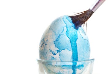 Fırça ve mavi suluboya ile Paskalya yumurtası boyası ve fırça, kopya alanı olan beyaz bir arkaplanda izole edilmiş, seçilmiş odak