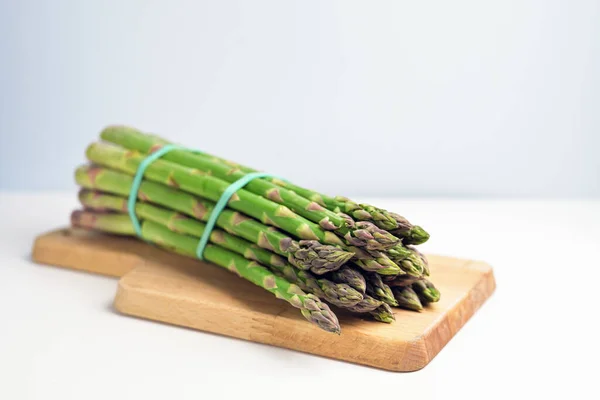 Biologische Groene Asperges Een Houten Snijplank Lichtgrijze Achtergrond Met Kopieerruimte — Stockfoto