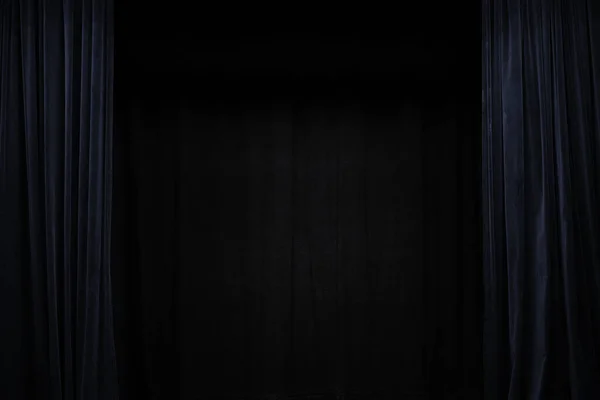 Very dark blue velvet curtain on the sides of a black theatre stage, background frame with large copy space