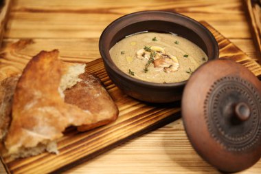 Kil tencerede kalın mantar kremalı çorba. Uygun dengeli beslenme. Vejetaryen sebze çorbası. Ahşap bir tahtanın üzerindeki tabak menüsü. Güzel kokulu sıcak yemek. Yüksek kalorili yiyecekler..