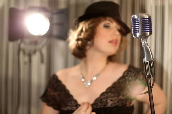 Girl singing in a retro microphone. Recording a clip in the studio of a professional singer. Close up face of singer with microphone on smoky gray background. The singer sings a song on stage.