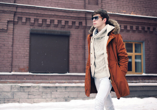 Fashion man wearing a jacket walking in city over brick wall bac