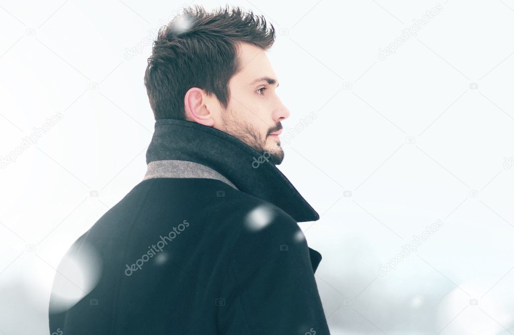 Portrait of fashion handsome elegant free man in winter snowstor