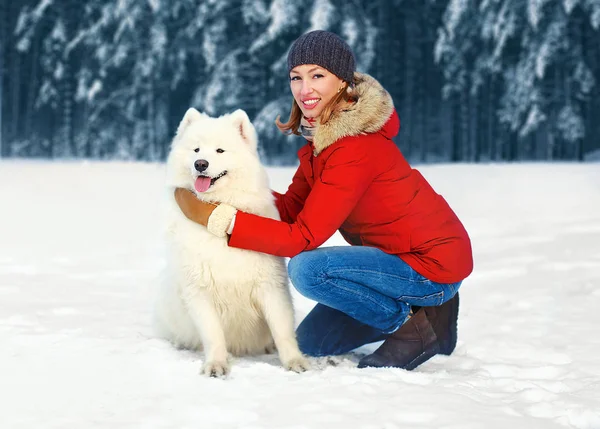 Feliz mujer sonriente con perro Samoyedo blanco en la nieve caminando en wi —  Fotos de Stock