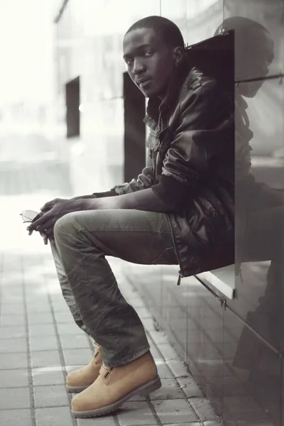 Модный молодой африканский мужчина, сидящий в городе, просмотреть профиль — стоковое фото