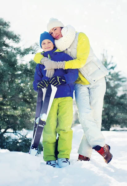 Здоровый образ жизни семьи! Мать обнимает сына с лыжами в руках — стоковое фото