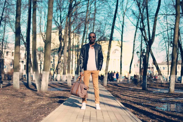 Moda modello uomo africano indossando giacca di pelle nera con borsa — Foto Stock