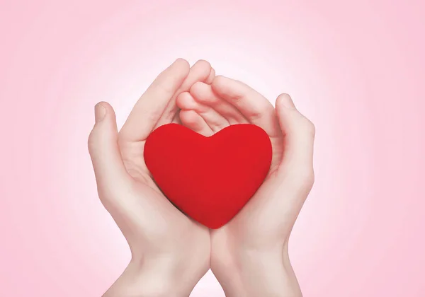 Ανοικτά χέρια κρατώντας δείχνει κόκκινη καρδιά σε ροζ φόντο — Φωτογραφία Αρχείου