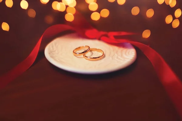 Hochzeit zwei goldene Ringe auf dem Tisch mit roter Schleife über Celebra — Stockfoto