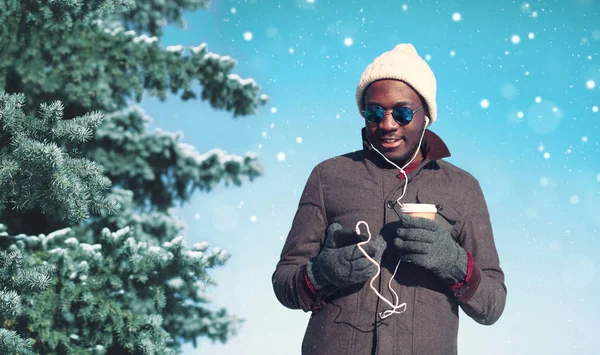 Inverno giovane sorridente africano uomo godendo ascoltare musica su sma — Foto Stock