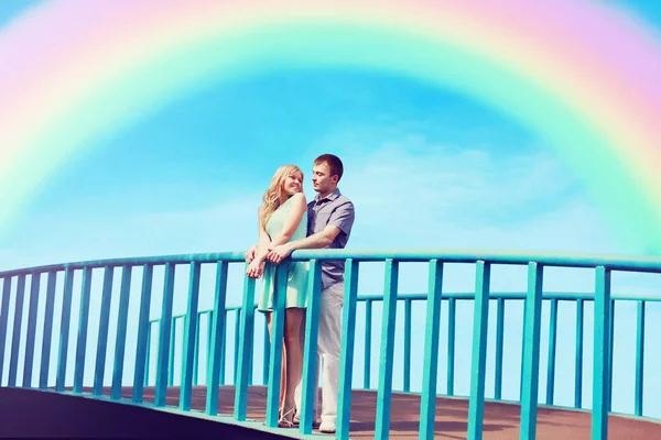 Feliz casal muito jovem no amor na ponte sobre o céu azul e — Fotografia de Stock