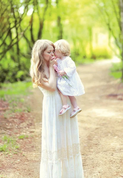 Happy mother tenderly kissing her baby holding on hands in sprin — Stock Photo, Image