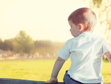 Küçük çocuk çocuk dalgın uzakta açık havada seyir oturuyor bir