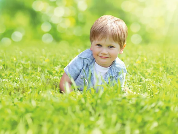 Portrait cute smiling child playing lying on grass in sunny summ — Stock Photo, Image
