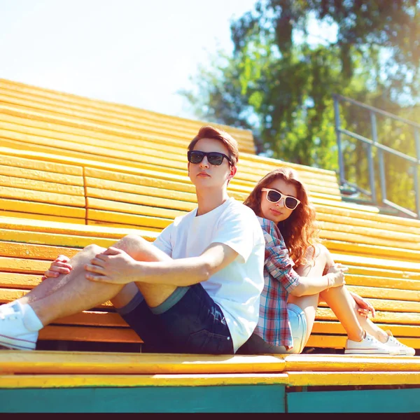 Moda jovem casal em um óculos de sol estão sentados no banco ci — Fotografia de Stock