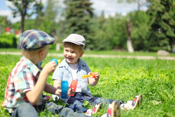 Glada två pojkar barn sitter på gräset och spela ut — Stockfoto