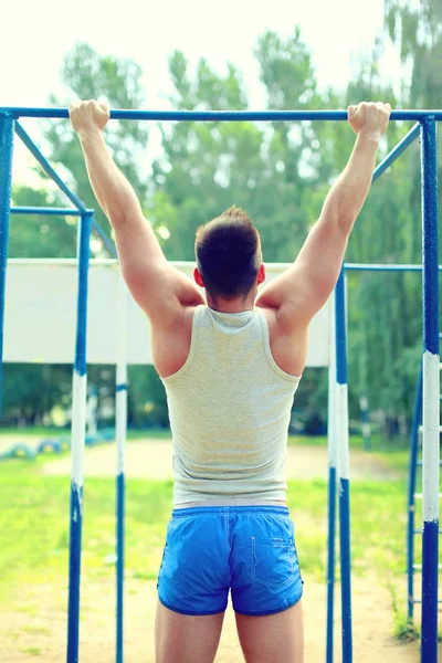 Sport, street workout concept - athlete doing pull ups on the ho