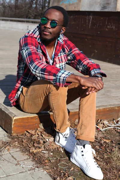 Fashion portrait african man with earphones listens to music sit — Stock Photo, Image