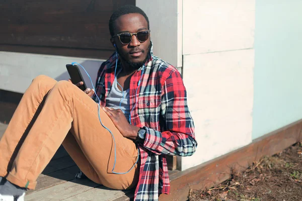 Modeporträt junger afrikanischer Mann sitzt und hört Musik auf T — Stockfoto