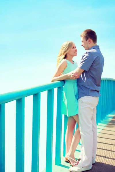 Happy loving couple stands on the bridge over a blue sky at city — Stock Photo, Image