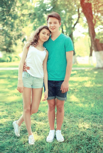 Jovens adolescentes casal feliz fica na grama no parque — Fotografia de Stock