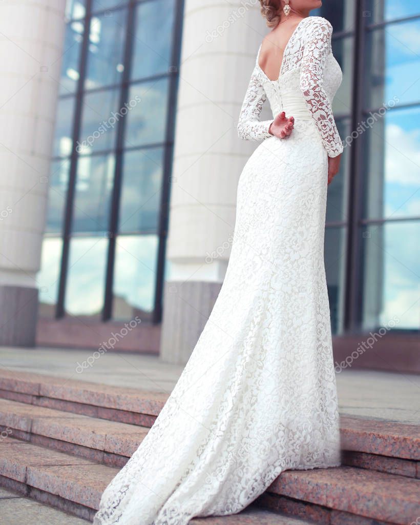 Elegant woman bride in white wedding lace dress posing in the ci