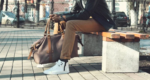 Moda hombre africano elegante con bolsa se sienta en el banco en el pa — Foto de Stock