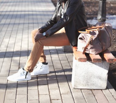 Moda adam çanta ile şehir parkta bir bankta oturur