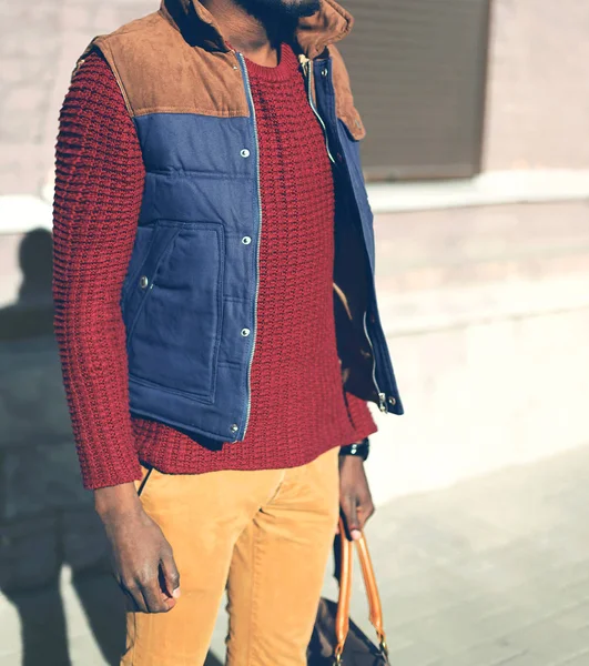 Fashion man in a red knitted sweater, vest jacket stands in the