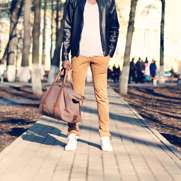 Человек моды стоит с сумкой в руке на открытом воздухе крупным планом — стоковое фото