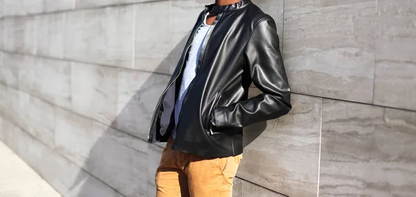 Hombre de moda con una chaqueta de cuero negro en la ciudad en un gris —  Fotos de Stock
