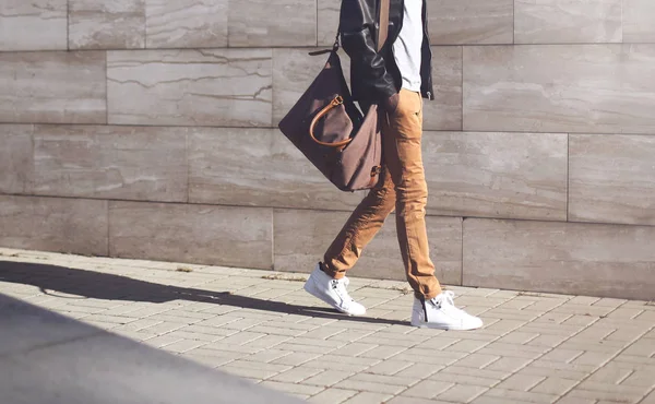 Hombre de moda con chaqueta de cuero negro con bolso caminando en la víspera —  Fotos de Stock