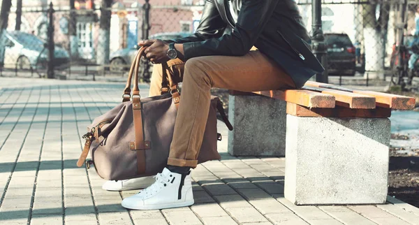 Μόδα ανθρώπου με τσάντα κάθεται σε ένα παγκάκι σε κοντινό πλάνο πόλη — Φωτογραφία Αρχείου