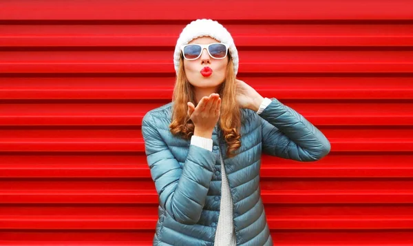 Moda mulher soprando lábios vermelhos envia um beijo de ar em um fundo — Fotografia de Stock