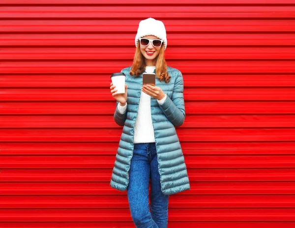 Moda joven mujer está utilizando el teléfono inteligente con la taza de café en un rojo — Foto de Stock