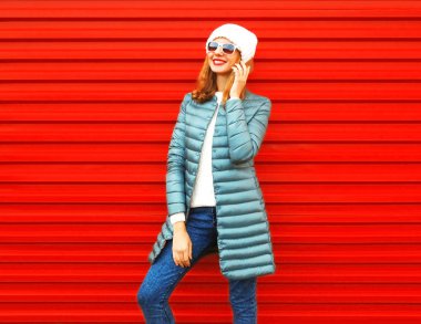 Moda kadın görüşmeler bir smartphone cep telefonu ile kırmızı bir arka plan üzerinde gülümseyen 