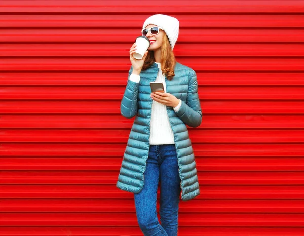La mujer joven de moda bebe café con un smartphone en una espalda roja — Foto de Stock