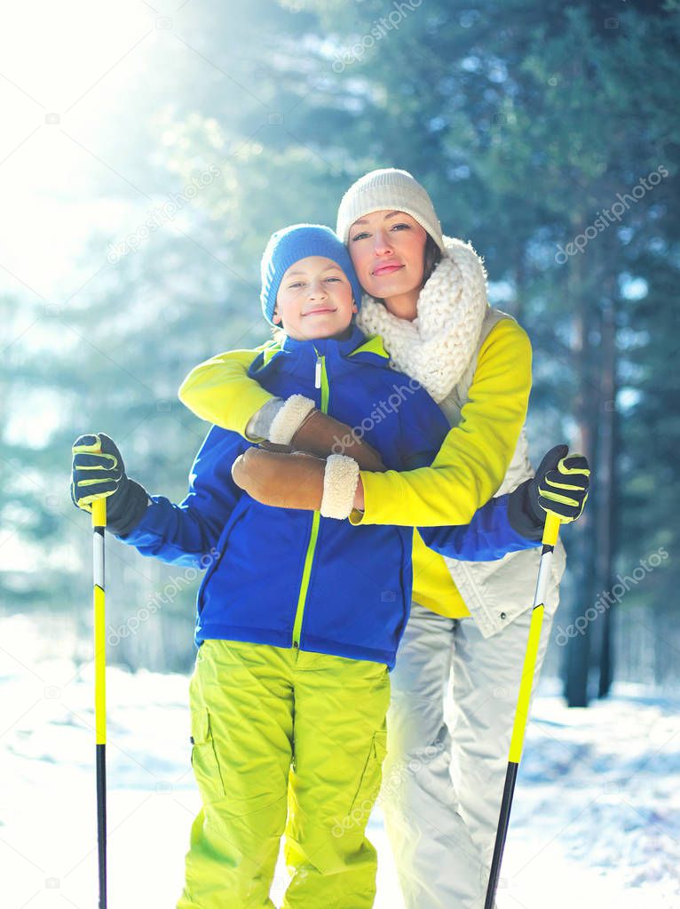 Winter portrait of mother hugs her son child on a ski in the for