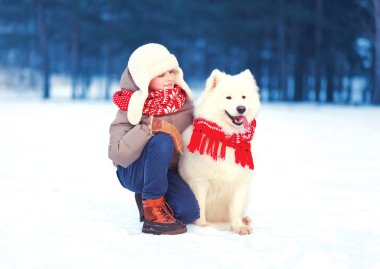 Mutlu çocuk çocuk ile beyaz Samoyed köpek kış günü içinde yürüyor