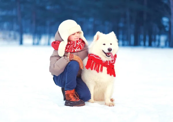 Szczęśliwe dziecko chłopiec jest chodzenie z biały pies samojeda w zimowy dzień — Zdjęcie stockowe
