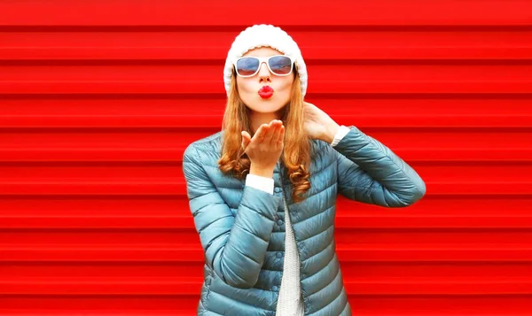 Moda donna soffiando rosso labbra invia un aria bacio su uno sfondo — Foto Stock